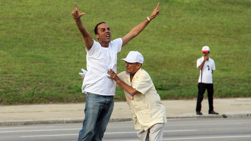 A Cuban dissident is prevented by security personnel from approaching the popemobile