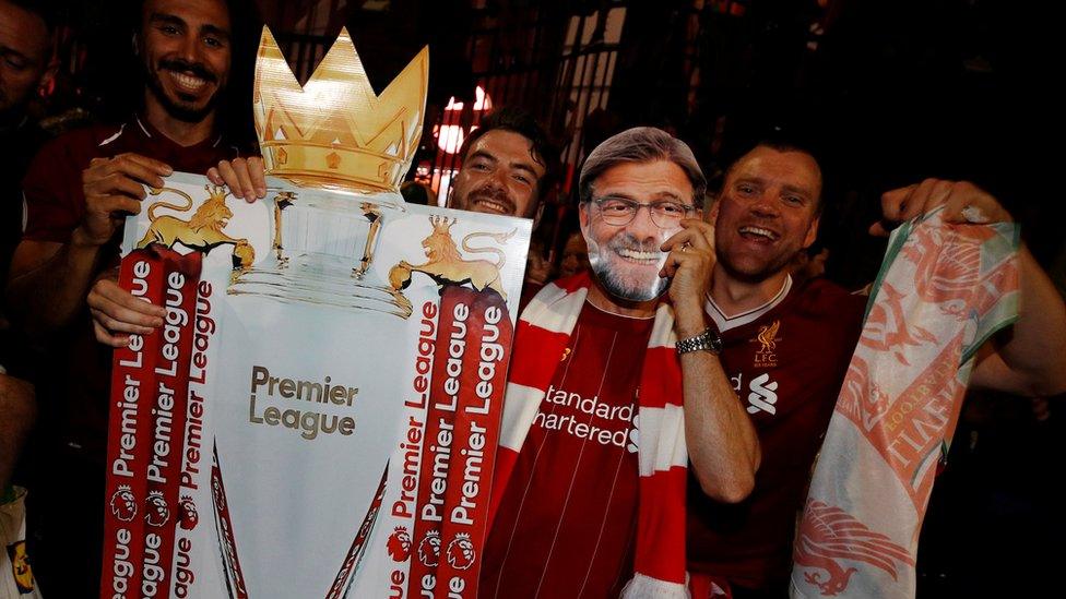 Fans holding a replica trophy wearing a Jurgen Klopp mask