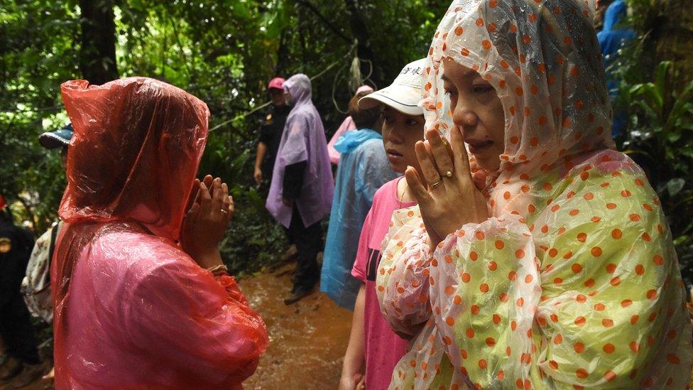 Family members and relatives pray at the entrance of Tham Luang cave while rescue personnel conduct operations to find the missing members of the children"s football team along with their coach at the cave in Khun Nam Nang Non Forest Park in Chiang Rai province on June 26, 2018