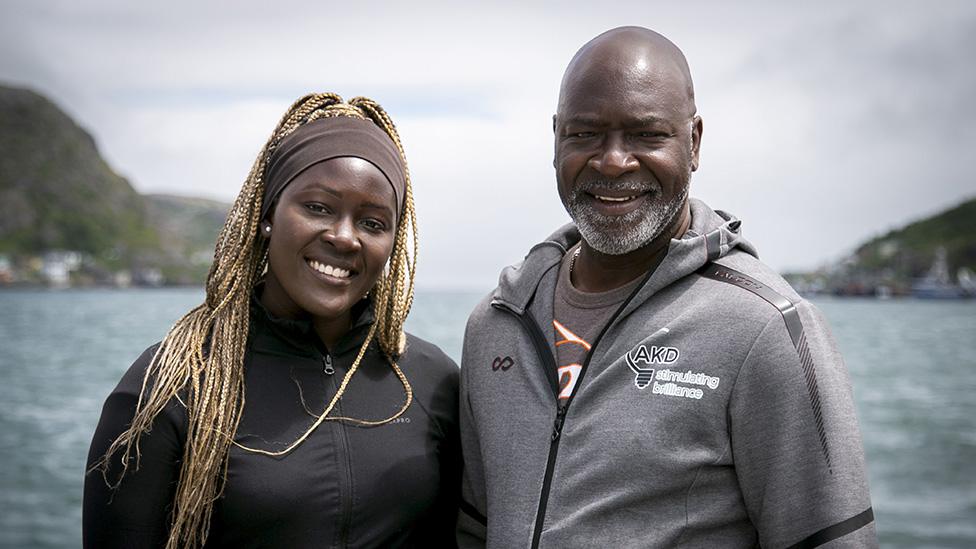 Monique and Ladi smiling, in front of a body of water