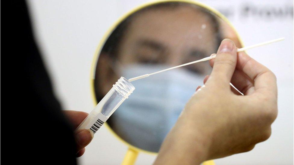 A health worker demonstrates how to take a coronavirus test