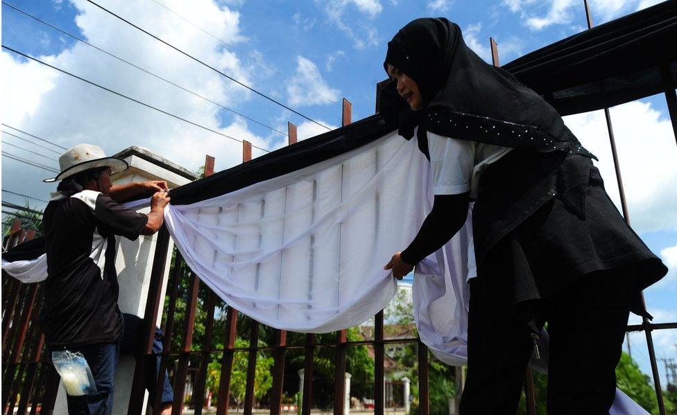 In this picture, Thai Muslim workers use symbolic black and white fabric to decorate a fence after the death of King Bhumibol Adulyadej, at the Narathiwat city hall in Thailand's southern province of Narathiwat, on 14 October, 2016.