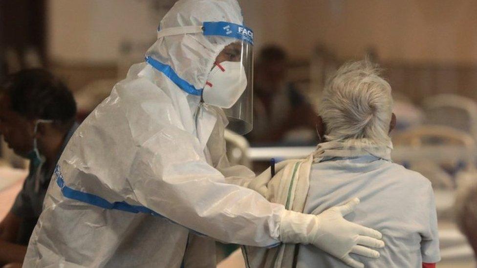 An Indian doctor wearing PPE examines a patient at a hospital in Delhi on 13 April 2021