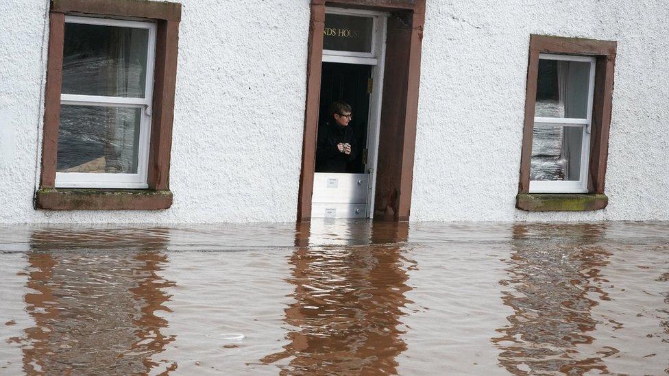 Karen watches the water from her doorway