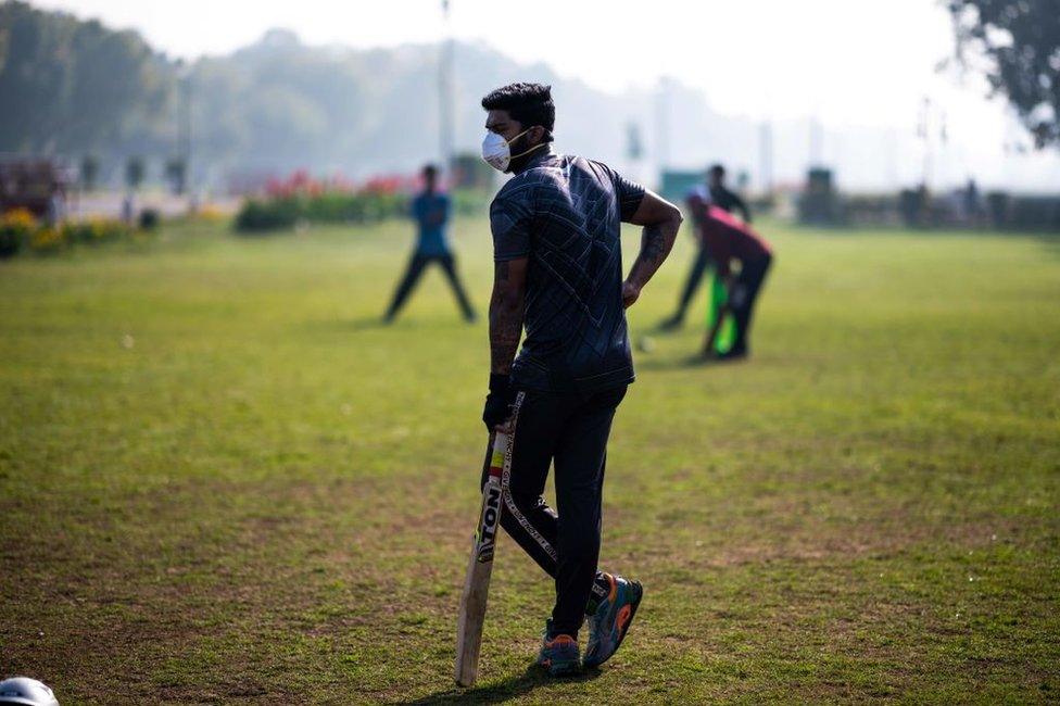 A youth (C) wearing a facemask as a preventive measure against the COVID-19 coronavirus plays cricket with his friends at a park in New Delhi on March 18, 2020.