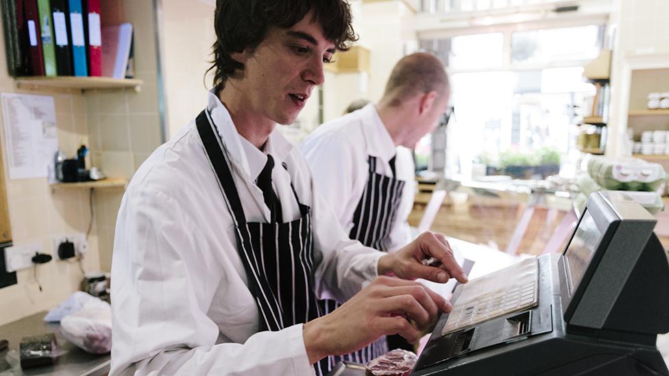 A butcher uses the till at a traditional butcher's shop in Dorset