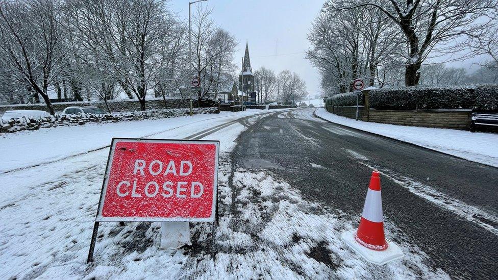 Road closed sign covered in snow