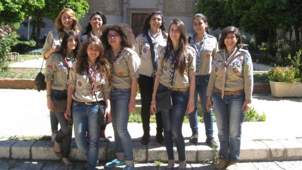 Nine girl guides in uniform on the pavement in the sunshine