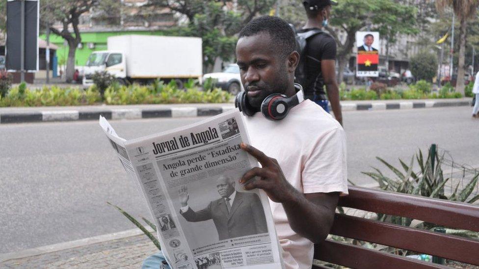 A man reads a copy of the Jornal de Angola newspaper with a headline about the death of former Angola President Jose Eduardo Dos Santos in Luanda on June 9, 2022