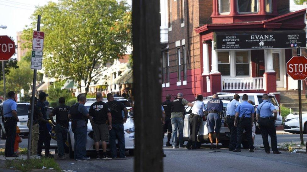 Police officers hold guns near the scene of a shooting in Philadelphia