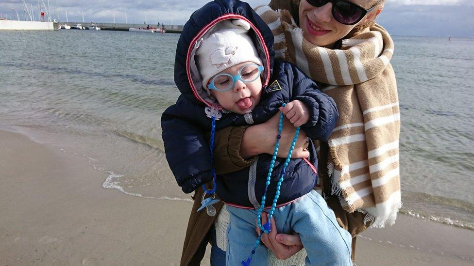 Mother with baby praying on a beach in Gdynia