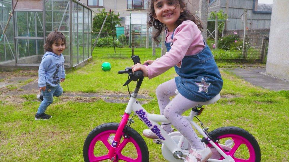 two children with a bike in a garden