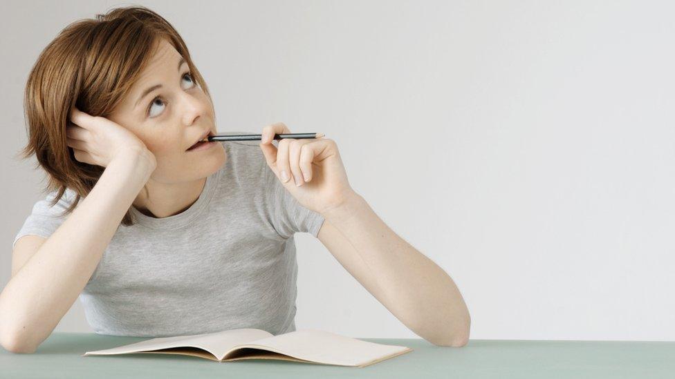 Young woman sitting at desk trying to write