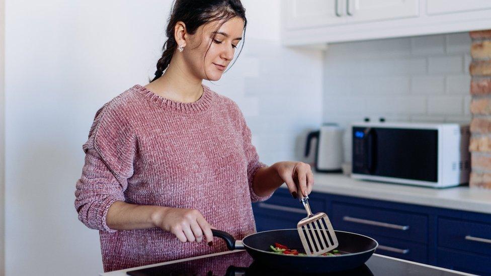 Young woman cooking on hob