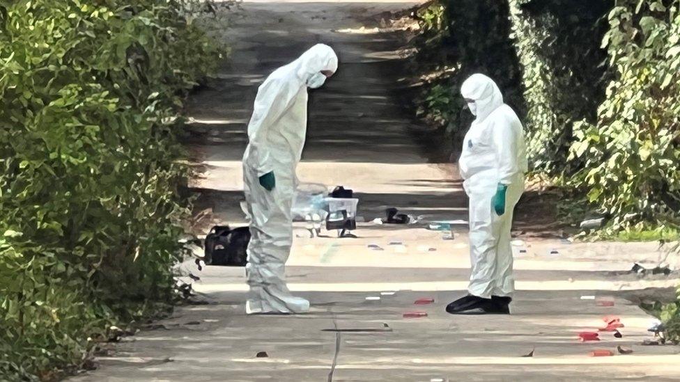 Crime scene investigators looking at the ground in Distillery Lane