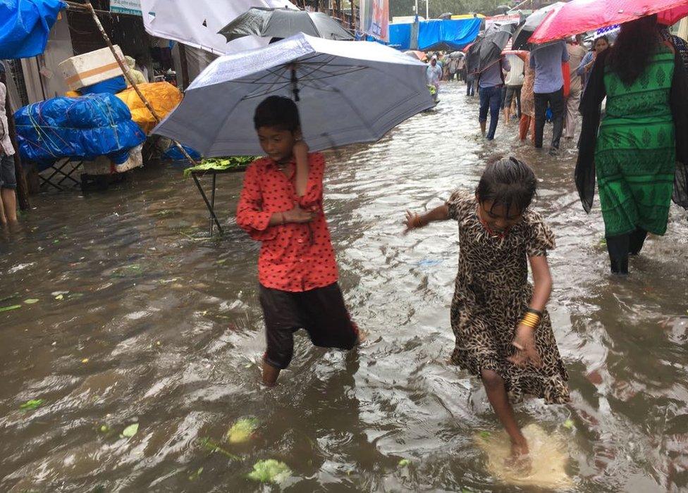 Two children with umbrellas on a flooded street