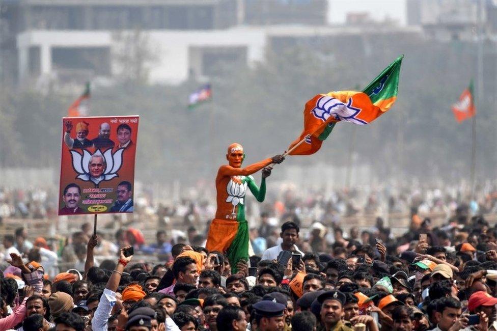 An Indian Bharatiya Janata Party (BJP) supporter waves a flag among the crowd of other supporters listening to Prime Minister Narendra Modi during the National Democratic Alliance (NDA) "Sankalp" rally in Patna in the Indian eastern state of Bihar on March 3, 2019