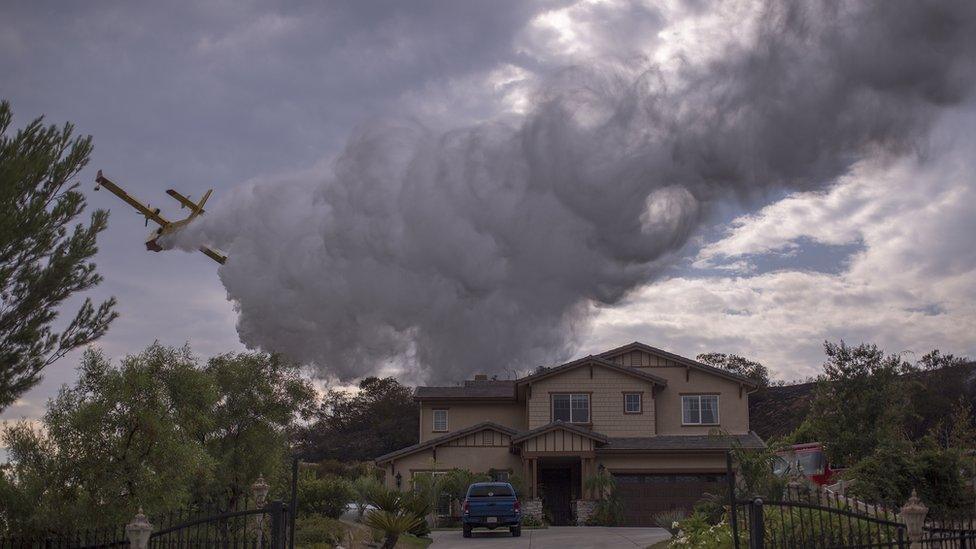 A Super Scooper CL-415 firefighting aircraft from Canada makes a drop to protect a house during the La Tuna Fire on September 3, 2017 near Burbank,