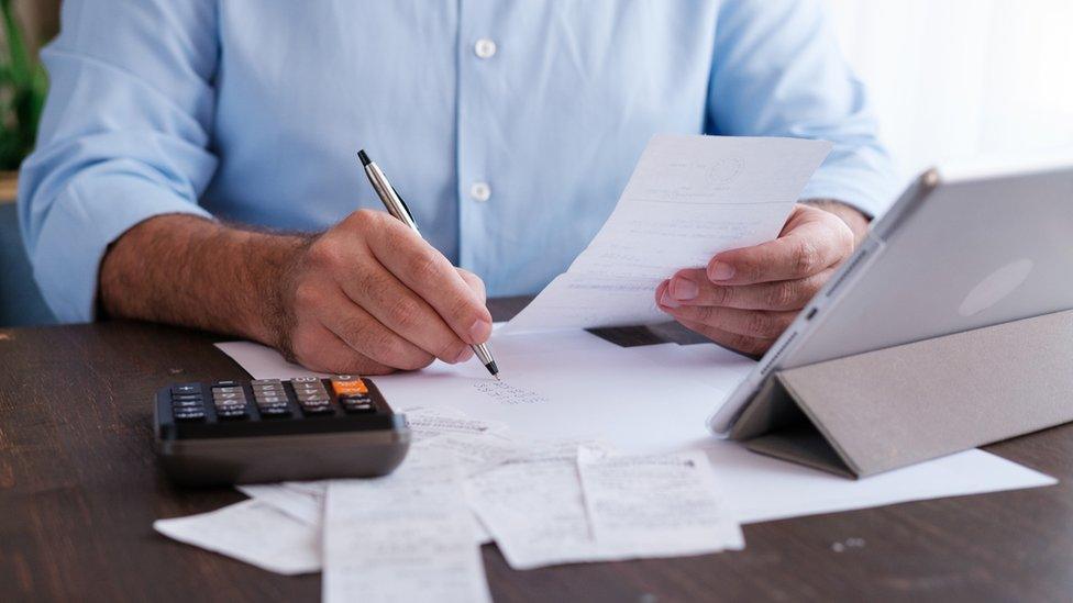 Man using calculator writing on piece of paper