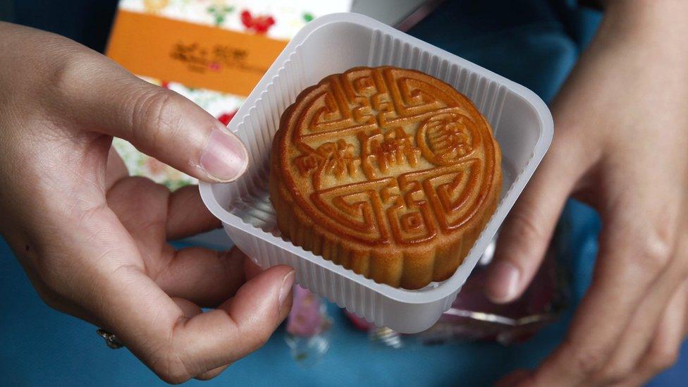 A college-level Indonesian student opens a box of moon cakes as part of an activity held to teach foreign students about the Mid-Autumn Festival at Jingshan Park in Beijing, China,