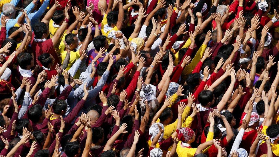 Filipino Roman Catholic devotees raise their hands in prayer during a procession to celebrate the feast day of the Black Nazarene on 9 January in Manila, Philippines