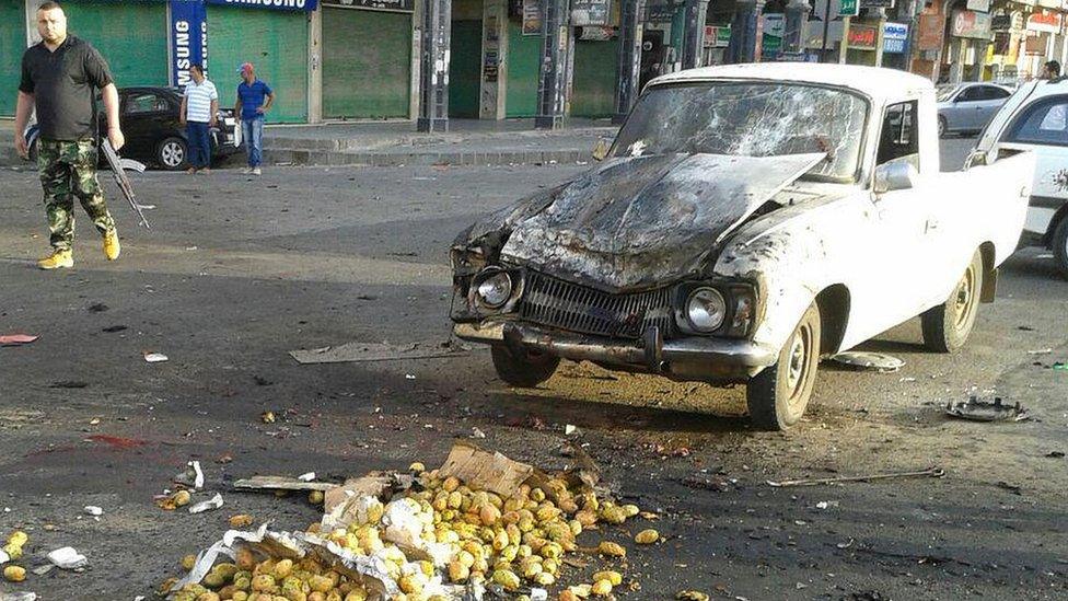 Picture from Syrian news agency (Sana) on July 25, 2018 shows a member of the security forces walking past a truck damaged in a suicide attack in Suweida