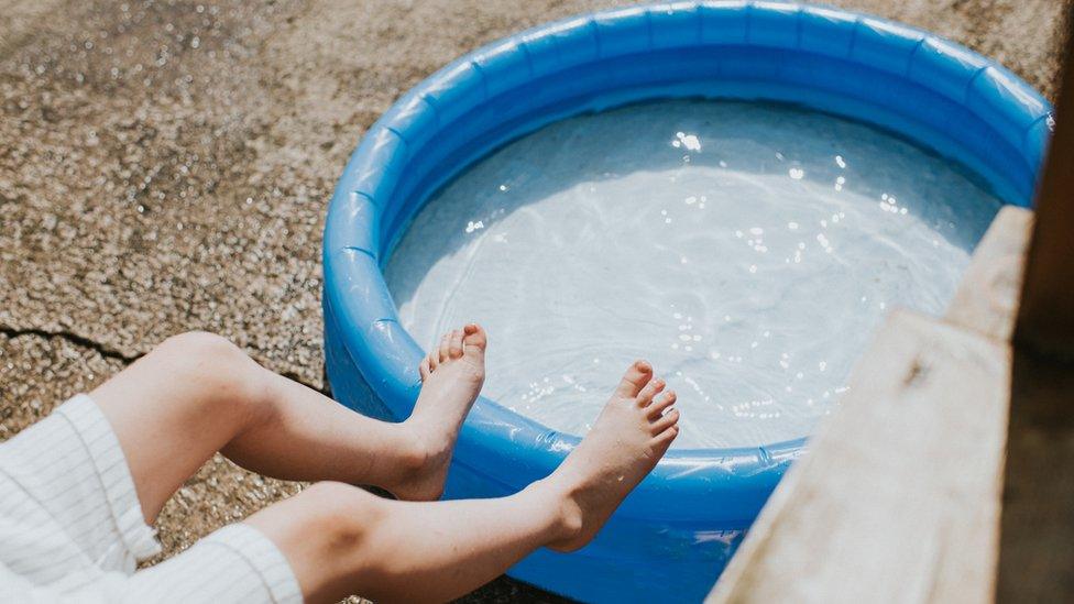 A person cooling off in a paddling pool