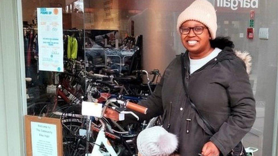 Woman and child stand with bike outside bike shop