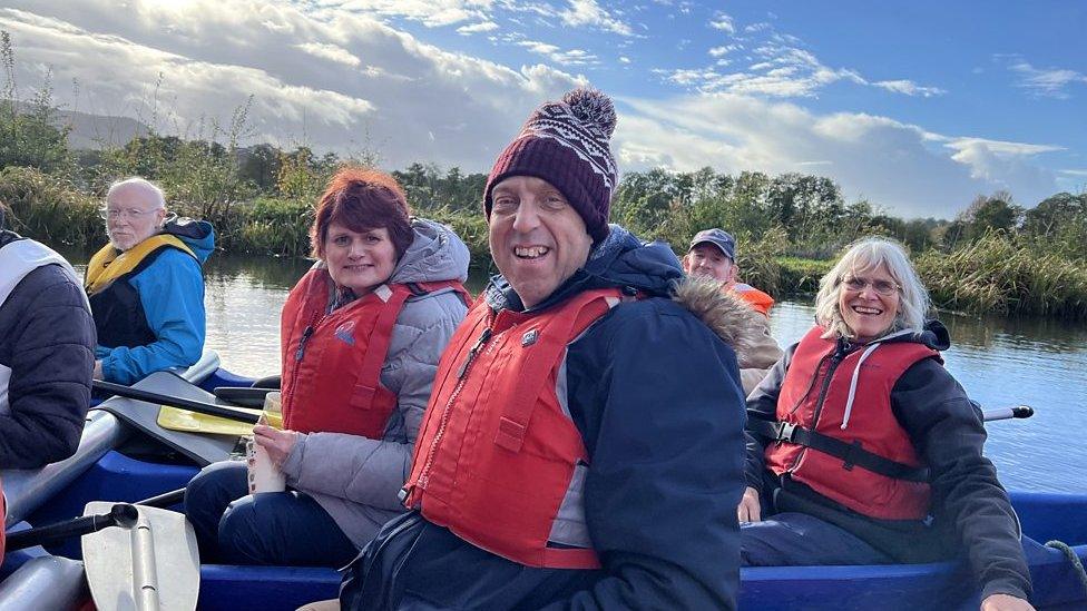 Three people on a canoe smiling