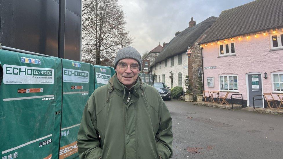 Nick Josephy looks into the camera dressed in a green winter coat, glasses and woolly grey hat.