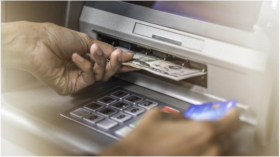 Stock image of person retrieving money from ATM