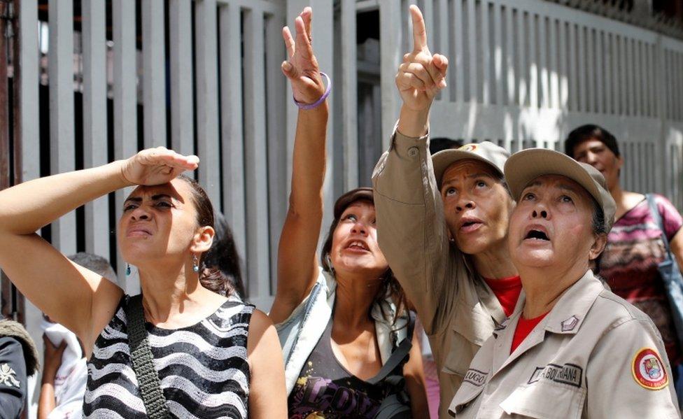 Militia members and civilians look at the damage on a skyscraper known as the "Tower of David" after an earthquake in Caracas, Venezuela