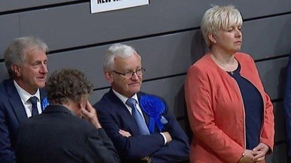 Conservative MPs Lia Nici and Martin Vickers looking unhappy standing against a wall with other candidates