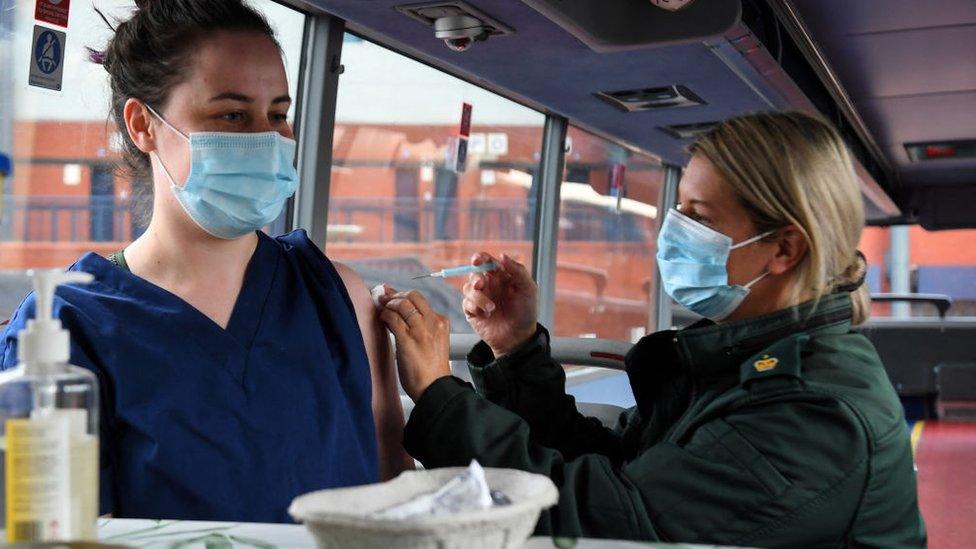 Cheryl Barr of the Scottish Ambulance Service, gives Fiona Douglas, 26, a vet from Falkirk, an injection of a Covid-19 vaccine on the Scottish Ambulance Service vaccine bus in Glasgow on July 28, 2021