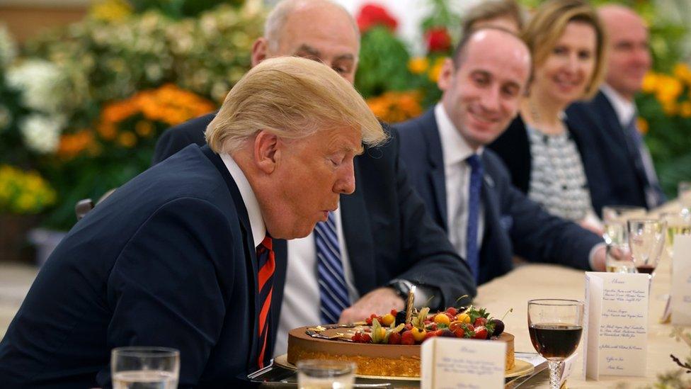 US President Donald Trump blowing out the candle of a birthday cake during lunch with Singapore's Prime Minister Lee Hsien Loong (not seen) in Singapore on 11 June 2018