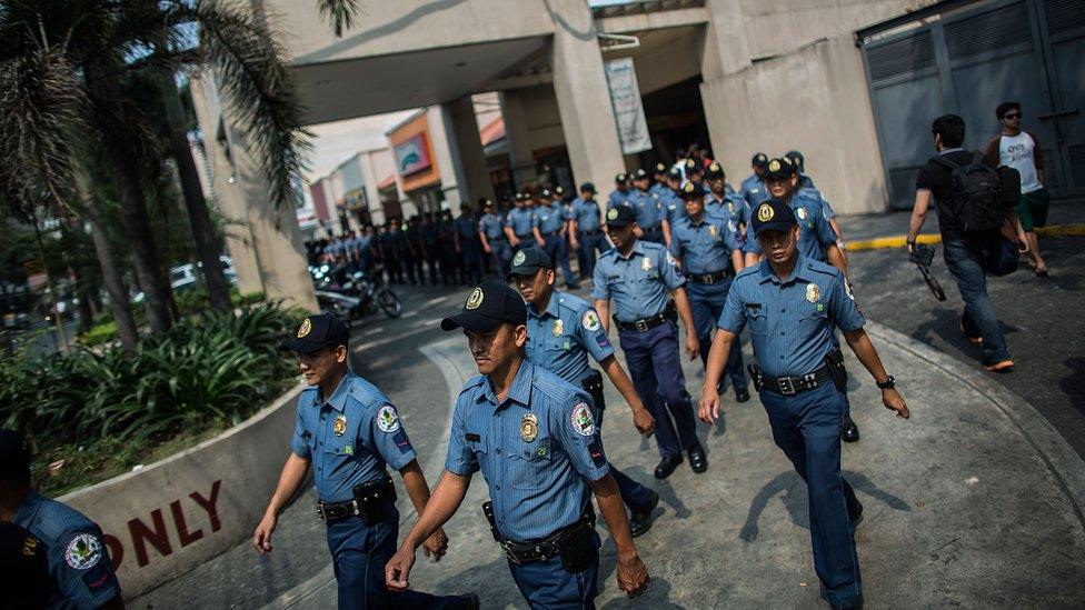 Dozens of police officers walk in file in Manila.