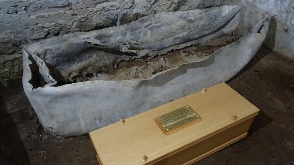 Original casket next to a new coffin that was made to hold the bone fragments that were found