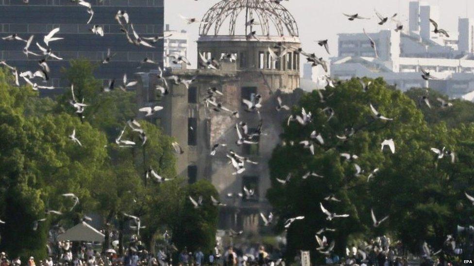 Doves fly over the Atomic Bomb Dome during the peace memorial ceremony marking the 70th anniversary of the atomic bombing at Hiroshima Peace Memorial Peace Park in Hiroshima (06 August 2015)