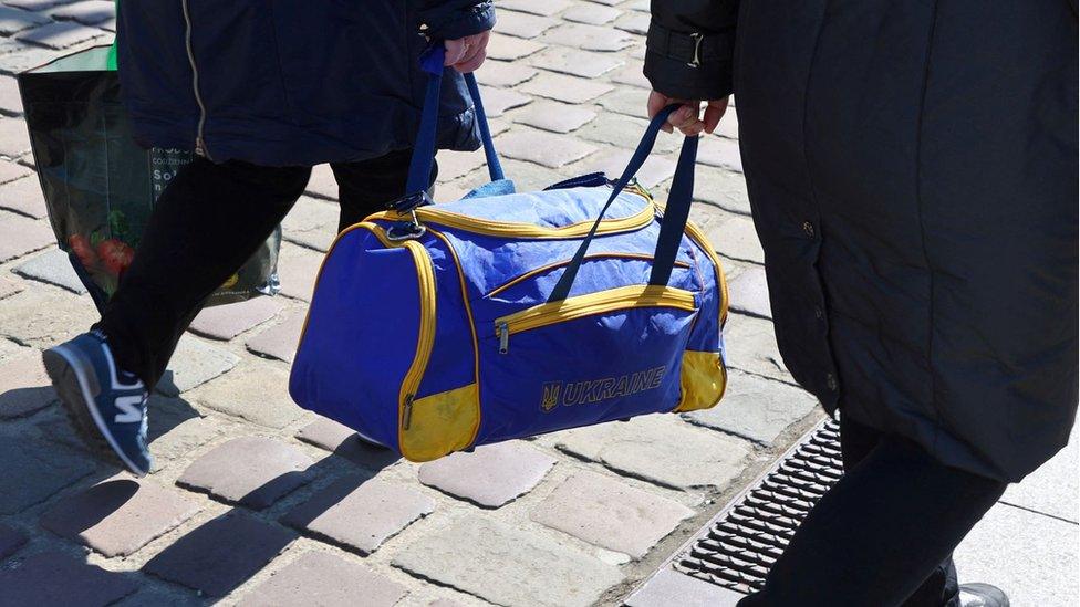 Refugees carrying a bag