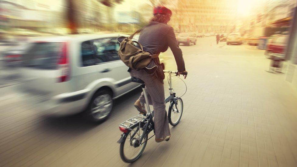 Cyclist on city road near car