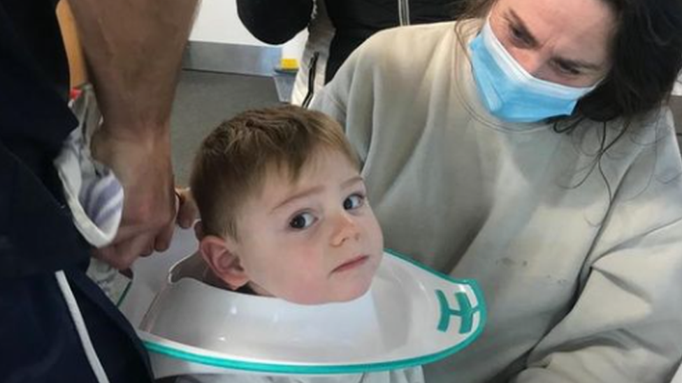 A toddler with a toilet training seat round his head