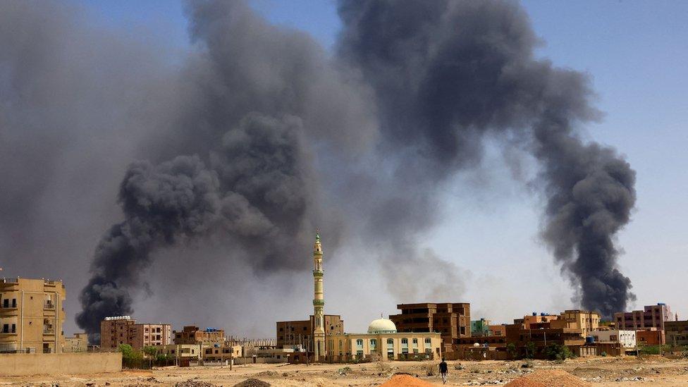 A man walks while smoke rises above buildings after aerial bombardment, during clashes between the paramilitary Rapid Support Forces and the army in Khartoum North, Sudan, May 1, 2023.