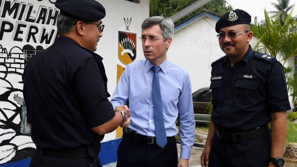 France's ambassador to Malaysia Frederic Laplanche with police officers