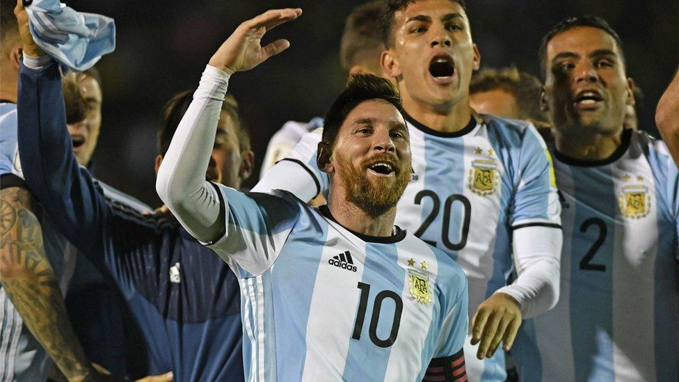 The Argentinean team jump up and down behind Messi, in their blue and white striped tops.