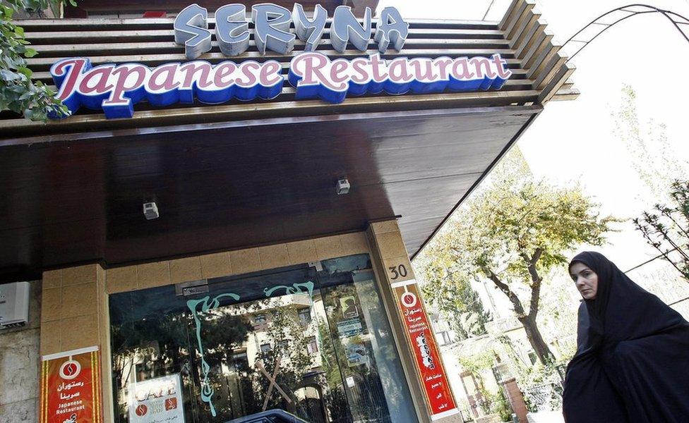 An Iranian woman walking past a Japanese restaurant in Tehran