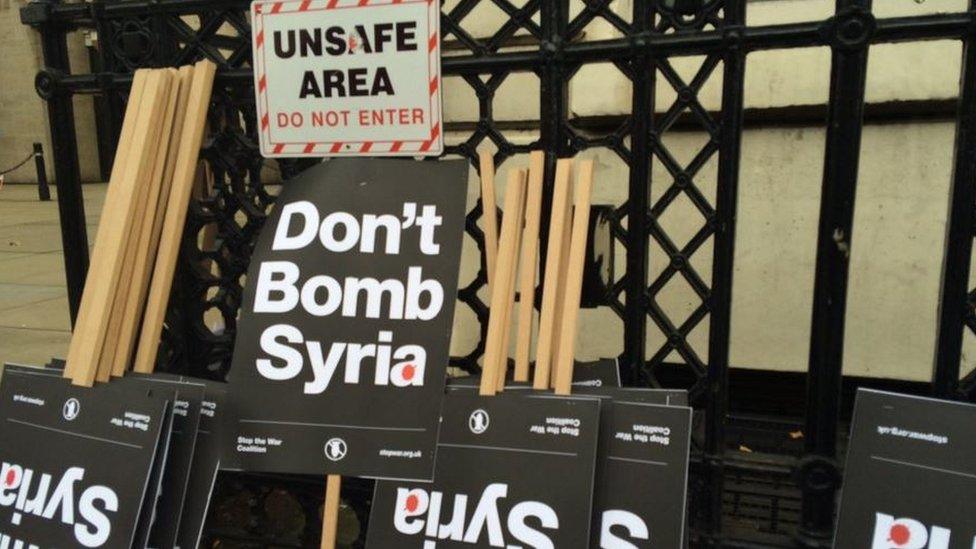 Placards reading "Don't Bomb Syria" put beside "Unsafe area. do not enter" warning sign outside Whitehall