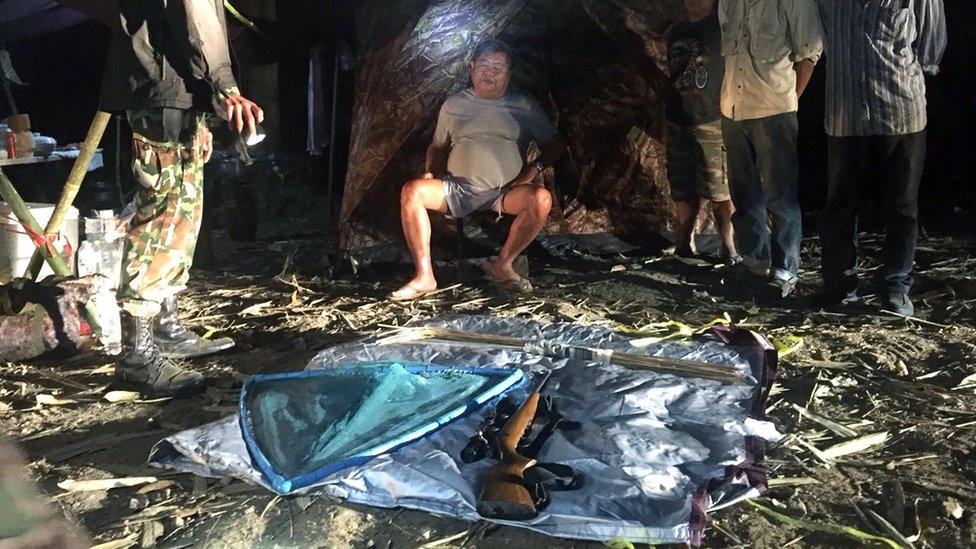 A handout photo made available by the Department of National Parks, Wildlife and Plant Conservation (DNP) shows a park ranger arresting Thai construction tycoon Premchai Karnasuta (C), president of Italian-Thai Development Plc, and other three others suspected of poaching wildlife at their camping site in a prohibited area of the World Heritage Thungyai Naresuan Wildlife Sanctuary in Kanchanaburi province, Thailand,