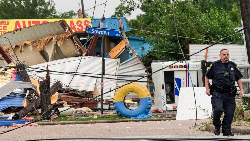 A police officer walks through storm damage