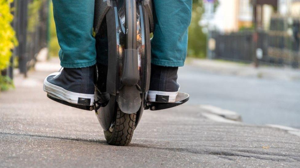 Man riding an electric unicycle on pavement