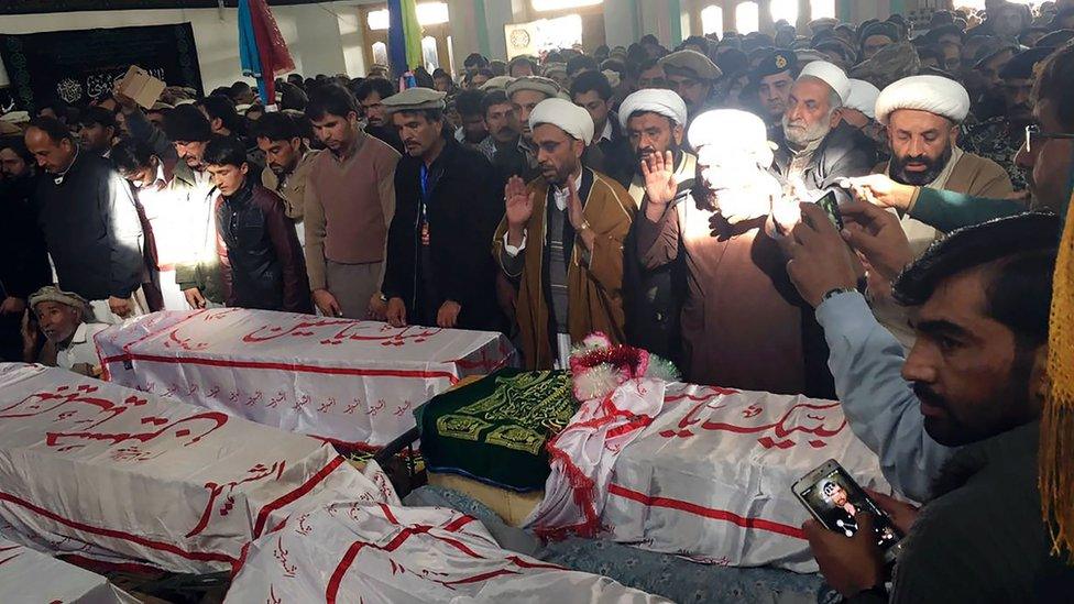 Pakistani mourners offer funeral prayers, gathered around coffins of the blast victims in Parachinar